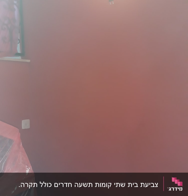 קיר צבוע באדום עם ניילון על רהיט